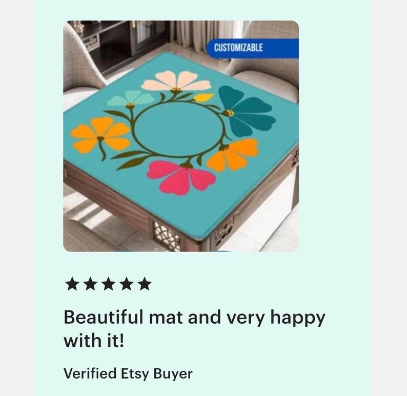 May include: Square table with a teal floral design. The table has a wooden frame and a teal top with a colorful floral pattern in orange, pink, and blue. The word "Customizable" is in the top right corner.