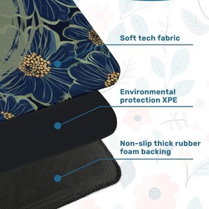 Op de afbeelding: Close-up van een muismat met bloemenpatroon. De bovenste laag is zachte technische stof, met milieubescherming XPE en een antislip dikke rubberen schuimrug. Het ontwerp heeft blauwe bloemen met gouden centra op een donkere achtergrond.