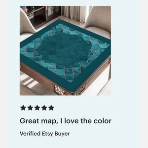 May include: A square table mat featuring a teal and dark blue Moroccan-style quatrefoil pattern with thin gold outlines. The mat has a solid dark teal border and is positioned on a wooden table surface with a lattice-style base design.