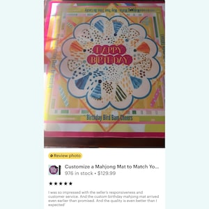 May include: A colorful birthday-themed mahjong mat with the words "HAPPY BIRTHDAY" in the center. The mat features a floral design with various shapes and colors, including blue, green, and yellow. The text "Birthday Bird Bam Cheers" is also visible.