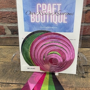 May include: A selection of nested, die-cut circles in green and pink, with a variety of metallic colour samples. The backing card features the text "CRAFT BOUTIQUE" and "OurKrazyKreations". The word "Wicked" is also visible.