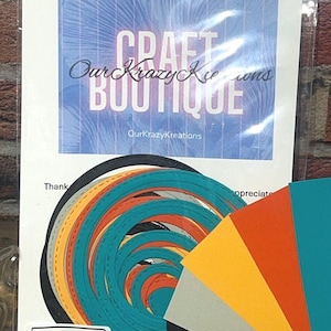 May include: A craft kit featuring a blue and white sign that reads "Craft Boutique" and "Our Krazy Kreations." The kit includes colorful paper cutouts in teal, orange, yellow, gray, and black, along with a "Dr Who" themed label.