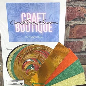 May include: A craft kit featuring the text "Craft Boutique" and "Our Krazy Kreations". The kit contains gold, orange, green, and black glitter and metallic paper, plus gold and red circular cutouts for crafting projects.