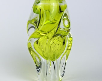 Puede incluir: Un jarrón decorativo de vidrio con un diseño único y fluido. El jarrón presenta un vibrante color verde lima translúcido arremolinado dentro de vidrio transparente. El jarrón tiene un cuerpo redondeado y una abertura acampanada, adecuado para exhibir flores o como pieza decorativa.