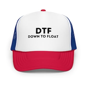 May include: A trucker hat with a white front panel, a red peak, and a blue mesh back. The hat features the text "DTF DOWN TO FLOAT" in black block letters.