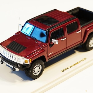 Può includere: Un modello di camioncino Hummer H3T del 2008 di colore bordeaux. Il pick-up in miniatura ha una griglia nera, un tetto apribile e ruote color argento. Il testo "2008 Hummer H3T" è stampato sulla base.