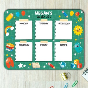 May include: A green dry-erase board with a colorful design featuring cartoon characters and school supplies. The board is divided into sections for each day of the week, with a notes section. The board has the text "MEGAN'S to do list" at the top.
