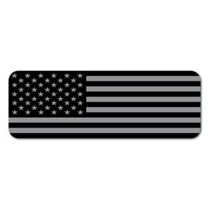 May include: A rectangular sticker featuring a stylized American flag design. The flag's stars are gray on a black background, with gray and black horizontal stripes. The sticker has rounded corners.