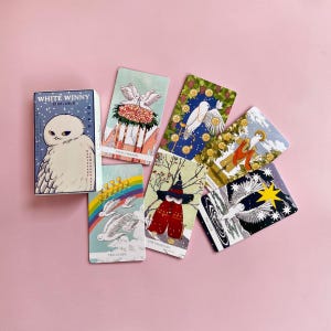 May include: The White Winny Tarot Deck box featuring a white owl illustration, alongside six tarot cards displaying various owl-themed artwork, including Four of Wands, Ten of Cups, The Magician, and The Star, all with colourful, detailed designs.
