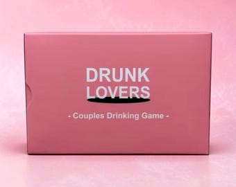 May include: A rectangular pink box for a drinking game. The front features the white text DRUNK LOVERS in a bold sans-serif font, with a black shadow effect underneath the word LOVERS, and the text - Couples Drinking Game - below it.
