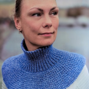 Peut inclure: Gros plan d'une femme portant un col en tricot bleu. Le col est fait d'un fil doux et texturé et a un design simple et élégant.