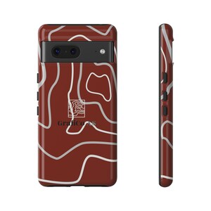 Puede incluir: Una funda de teléfono marrón con un diseño abstracto blanco y el texto "Grafico.AS". La funda tiene un borde negro y un recorte para la cámara.