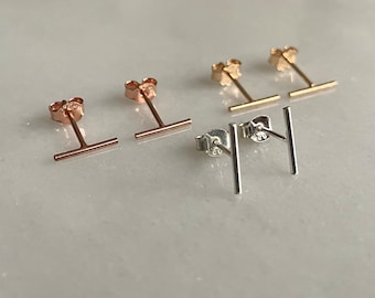 May include: Three pairs of minimalist bar earrings in gold, rose gold, and silver. Each earring features a thin, straight bar.