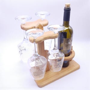 Może przedstawiać: Drewniany stojak na kieliszki i butelki do wina z butelką wina i trzema kieliszkami. Na kieliszkach widnieje napis "You are the things". Butelka wina jest zielona z korkiem i etykietą.