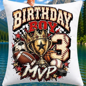 May include: A white square throw pillow featuring a graphic print with the text "BIRTHDAY BOY" and "MVP". The design includes a gold trophy with a star, a football, a rugby ball, a basketball, a baseball, and a large number 3.
