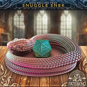 May include: A dice rolling tray shaped like a coiled snake with a teal and silver d20 die inside. The snake is a metallic pink and silver color with a textured, scaly surface. The tray is on a wooden surface with a 2025 "Year of the Snake" logo in the lower right corner.