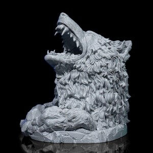 May include: A gray wolf head sculpture with an open mouth, revealing sharp teeth. The sculpture has detailed fur and sits on a rocky base. The background is black.