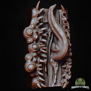 Puede incluir: Escultura marr&oacute;n impresa en 3D con un dise&ntilde;o grotesco. Presenta un fondo de tablones de madera, un gran ap&eacute;ndice texturizado en forma de lengua y varias protuberancias espinosas en forma de ojo. El logotipo "Miniatures of Madness" es visible.