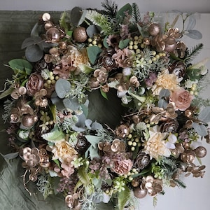 Op de afbeelding: Een decoratieve krans met kunstbloemen, groen en gouden ballen. De krans bevat rozen, hortensia's en eucalyptusbladeren in crème, roze en groene tinten. Ideaal voor seizoensgebonden woondecoratie en biedt een vleugje elegantie.
