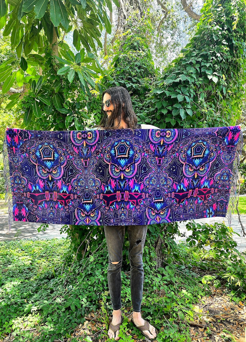 May include: A large, colourful tapestry featuring a repeating pattern of owls with geometric designs in shades of purple, pink, and blue. The tapestry has fringe on the edges.