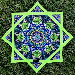 May include: A square, star-shaped textile with a vibrant design featuring green foxes, blue and purple foliage, and a central floral pattern. The outer border is a bright green, and the text "FLURRECT STUDIOS" is visible.