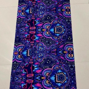 May include: A long, rectangular scarf with a dark blue background and a colourful, intricate pattern of owls and geometric shapes. The scarf has a fringe on both ends.