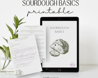 May include: A digital tablet displays a "Sourdough Basics" printable guide with a bread illustration. Two printed pages with text and illustrations are in front of the tablet. The text "Sourdough Basics" and "Wildflour Soul" are visible.