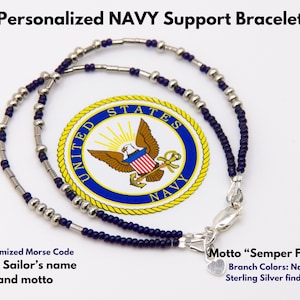 May include: A navy blue and silver beaded bracelet with a heart charm and a clasp. The bracelet is personalised with Morse code, a sailor's name, and a motto. The bracelet is displayed on a white background with the United States Navy seal.