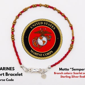 May include: A red and gold beaded bracelet with a sterling silver clasp and heart charm. The bracelet features the United States Marine Corps emblem and the motto "Semper Fi".