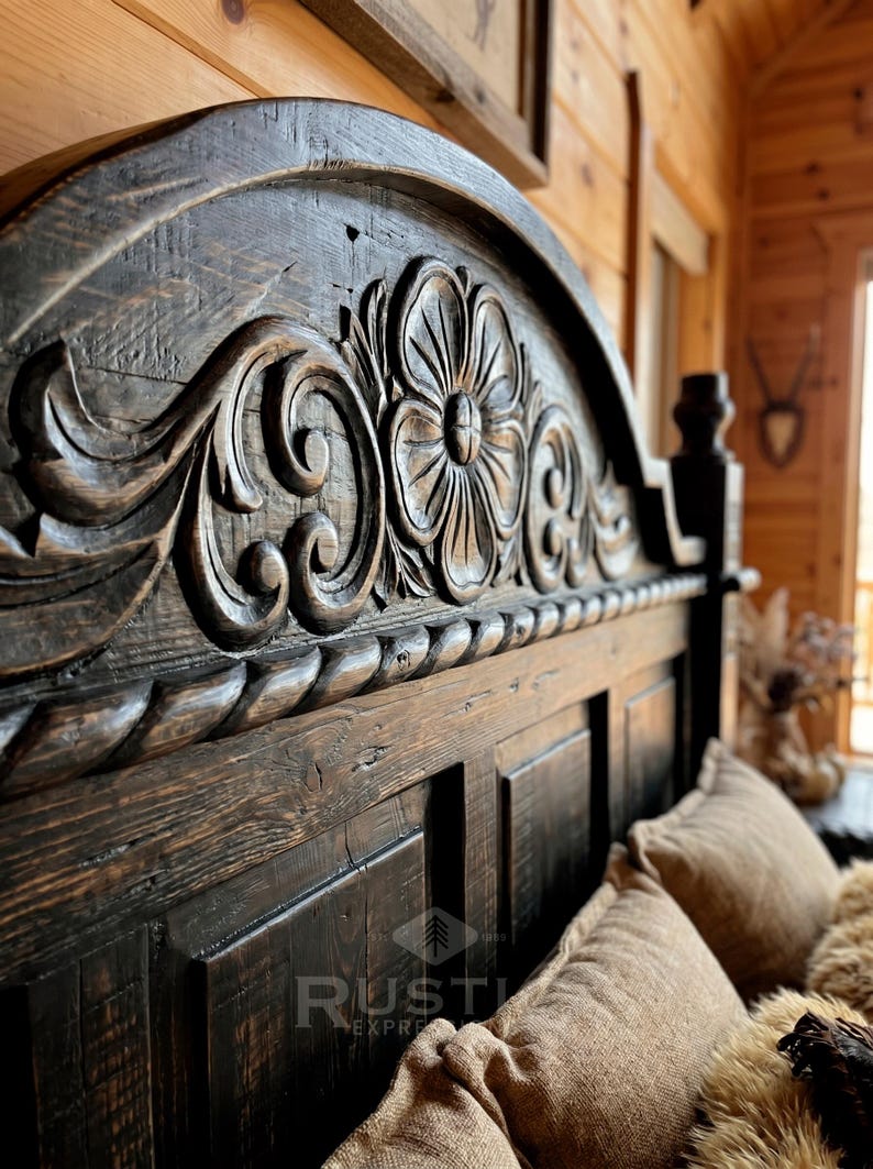 Pu&ograve; includere: Primo piano di una testiera in legno intagliato marrone scuro. La testiera presenta un motivo floreale con dettagli intricati e una finitura invecchiata. Il telaio del letto &egrave; parzialmente visibile, con cuscini e biancheria da letto.
