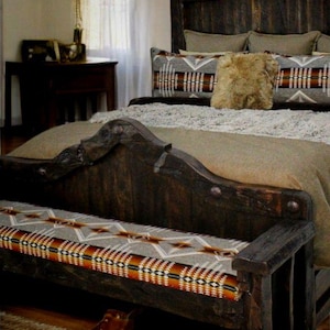 May include: Rustic bedroom set featuring a dark wood bed frame with a high headboard and a matching bench at the foot. The bed is adorned with patterned pillows and a faux fur cushion. Brown leather boots rest on a woven rug.