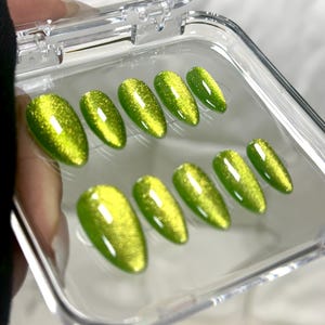 May include: A clear plastic case with ten green glitter press-on nails.