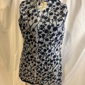 Puede incluir: Un chaleco azul marino con forro estampado en blanco y negro. El forro presenta un dise&ntilde;o de c&iacute;rculos y l&iacute;neas negras sobre un fondo claro. El chaleco se exhibe en un maniqu&iacute;.