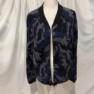 K&ouml;nnte beinhalten: Eine lang&auml;rmelige Bomberjacke mit Camouflage-Muster in Marineblau, Anthrazit und Schwarz. Die Jacke verf&uuml;gt &uuml;ber einen einfarbigen, schwarzen Rippstrickkragen, B&uuml;ndchen an den &Auml;rmeln und am Saum sowie einen durchgehenden Rei&szlig;verschluss in der Mitte.
