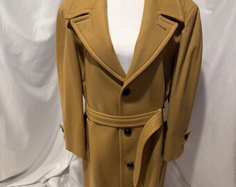 May include: A tan overcoat with a notched collar, button closures, and a matching belt. The coat is displayed on a mannequin and has long sleeves with buttoned cuffs. The coat is a classic style.