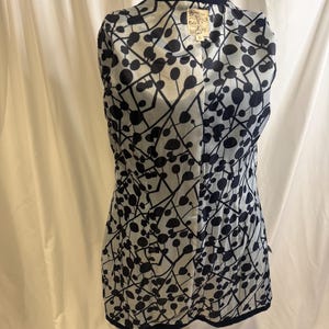 Puede incluir: Chaqueta azul marino con forro estampado en blanco y negro. El forro presenta un dise&ntilde;o de c&iacute;rculos y l&iacute;neas negras sobre un fondo claro. La chaqueta se exhibe en un maniqu&iacute;.