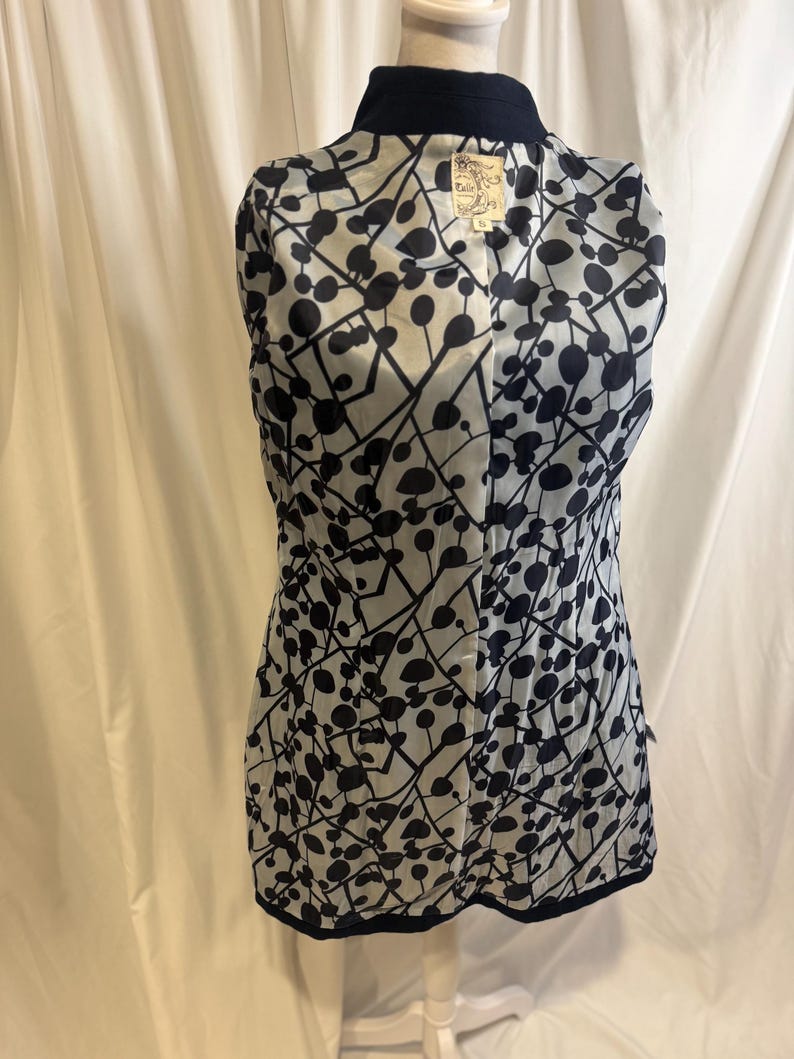 Puede incluir: Chaqueta azul marino con forro estampado en blanco y negro. El forro presenta un dise&ntilde;o de c&iacute;rculos y l&iacute;neas negras sobre un fondo claro. La chaqueta se exhibe en un maniqu&iacute;.