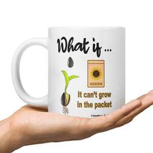 May include: White ceramic coffee mug with a black and white illustration of a sunflower seed sprouting. The text on the mug reads "What if... It can't grow in the packet".