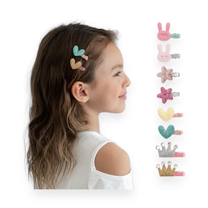 May include: A set of 8 glitter hair clips featuring various shapes and colors, including hearts, stars, crowns, and bunnies. The clips are pink, gold, green, and yellow.