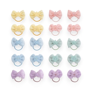 May include: Set of 18 pastel-coloured hair scrunchies with different embellishments, including stars, flowers, and crowns. The scrunchies are arranged in rows of three, with each row featuring a different colour and embellishment.