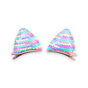 May include: Two pastel-coloured sequined cat ear hair clips. The ears are made of small, round, iridescent sequins in shades of pink, blue, green, and yellow. The clips are attached to metal hair clips.