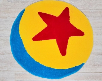 May include: A round rug featuring a yellow background with a large red star in the center. A blue crescent shape borders the bottom left side. The rug is a playful design, perfect for a child's room or playroom.