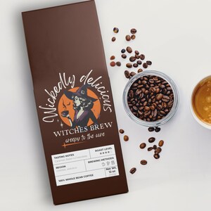Peut inclure: Un sac de café marron avec le texte "Witches Brew" et une illustration de sorcière, un bocal de grains de café et une tasse de café. Le sac est étiqueté "12 oz" et indique les notes de dégustation.