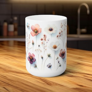 Könnte beinhalten: Weiße Keramiktasse mit einem Blumendesign mit rosa, weißen und lila Blüten mit grünen Stielen und Blättern.