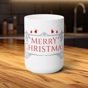 Könnte beinhalten: Weiße Keramiktasse mit blauem und rotem Design. Die Tasse zeigt den Text "Merry Christmas" in roten Buchstaben mit einem dekorativen Rand.