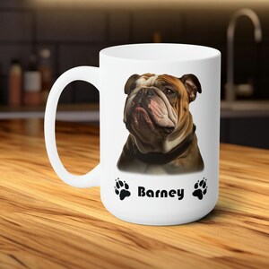 Puede incluir: Taza de cerámica blanca con una imagen de un bulldog marrón y blanco, el nombre del perro "Barney" está impreso debajo de la imagen, y dos huellas de patas negras están a cada lado del nombre.