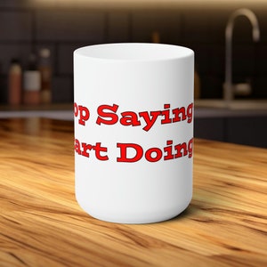 Könnte beinhalten: Eine weiße Keramiktasse mit dem Text "Stop Saying Start Doing" in Rot.