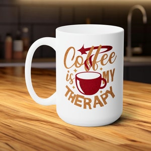 Può includere: Tazza da caffè in ceramica bianca con un design marrone e bianco che dice "Coffee is my therapy". Il design include anche una tazza da caffè rossa con vapore che esce da essa.