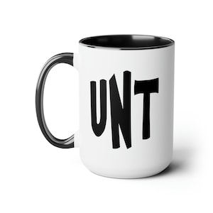 May include: A white ceramic mug with a black rim and handle. The mug has the word "UNT" printed in black on the front.