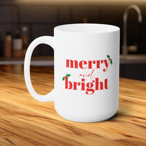 May include: White ceramic coffee mug with a red and green design. The mug has the text "merry and bright" printed on it.